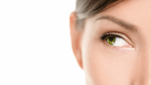 Close-up of a woman's green eye looking to the right, showing long lashes and well-groomed eyebrow.